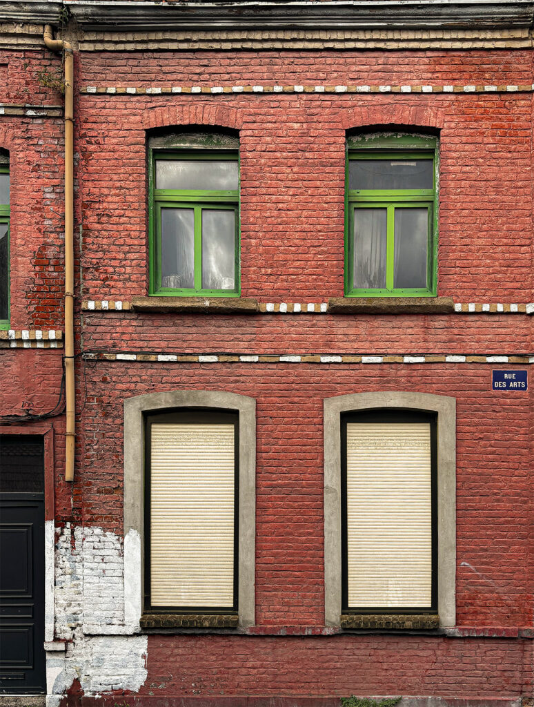 Old brick house façade with green woodwork sharply contrasting against the red brick. A 1930s house.