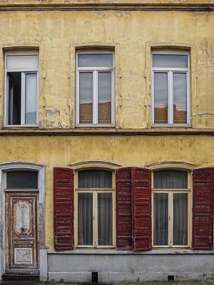 Yellow house façade with red shutters in the Trichon district of Roubaix.